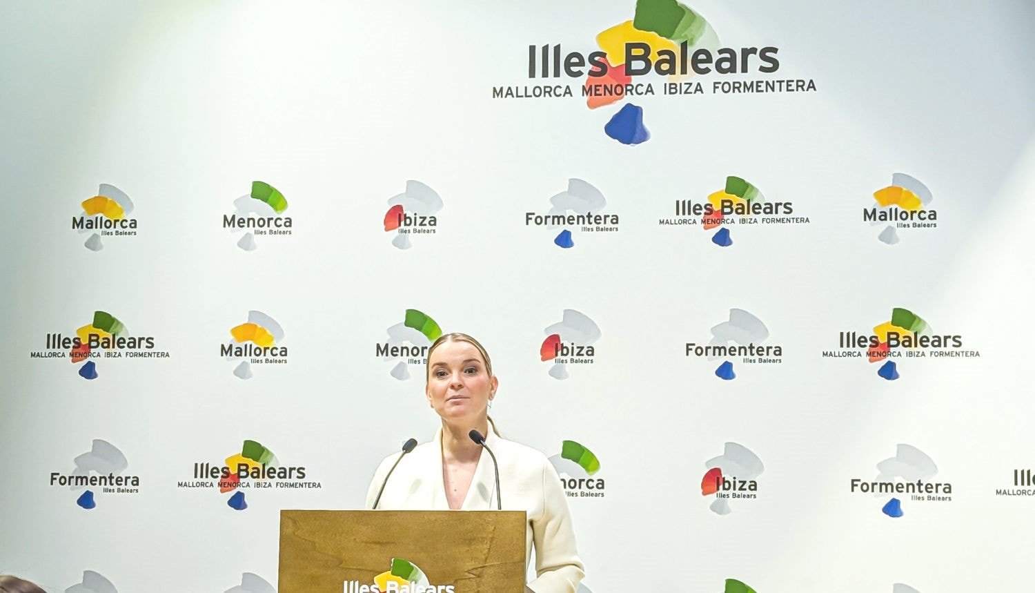 Präsentation vor Pressewand mit Logos der Baleareninseln und Rednerin am Pult