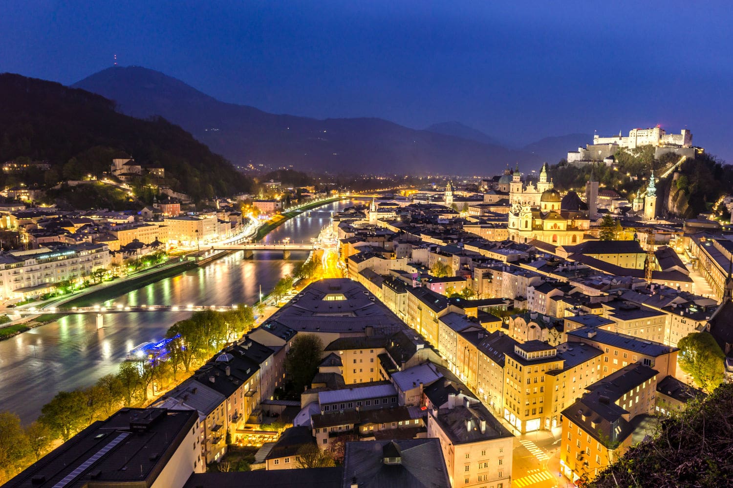 Panoramablick auf die hell erleuchtete Altstadt von Salzburg zur Blauen Stunde am Abend