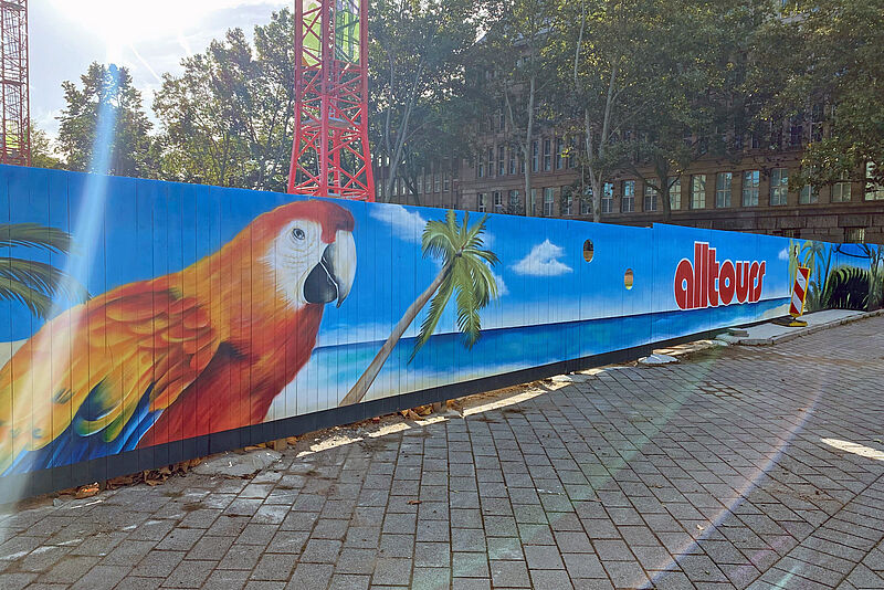 Eigens für Alltours entworfen: Urlaubsmotive und Firmenschriftzug am Bauzaun zum Rheinufer. Foto: mg