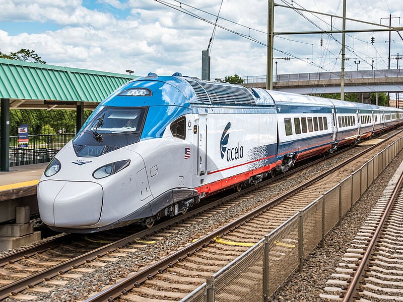 Ein moderner Schnellzug der Modellreihe Acela in den USA steht in einem Bahnhof vor einem leeren Bahnsteig.