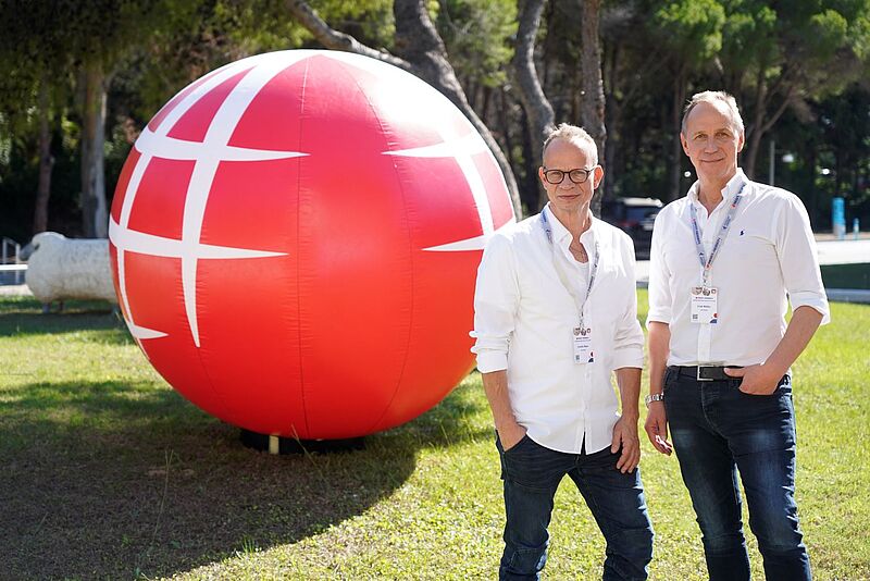 Cornelius Meyer und Frank Winkler mit einem großen roten Ball auf der Wiese