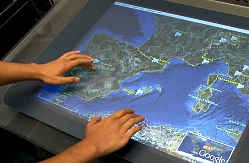 Mit der Hand auf der Landkarte Reiseziele suchen: Bistro auf der Microsoft Surface