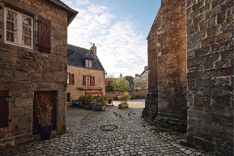 Blick auf die Altstadt von Pont-Croix in der Bretagne mit dem charakteristischen Kopfsteinpflaster sowie kleinen Gassen und alten Steinhäusern.