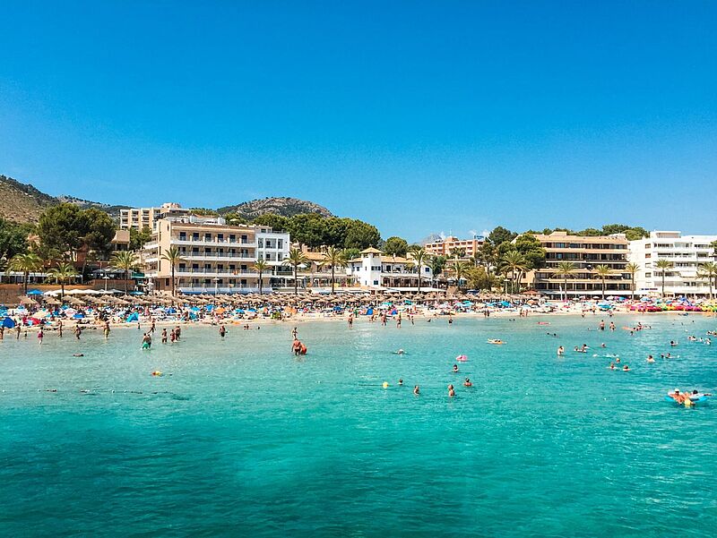 Sonnenstrand auf Mallorca mit türkisblauem Meer, Hotels und Badegästen – beliebtes Reiseziel für Sommerurlaub in Spanien.