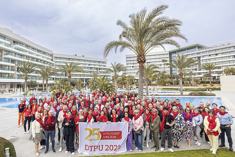 Menschen beim Gruppenfoto vor dem Pool eines Hotels