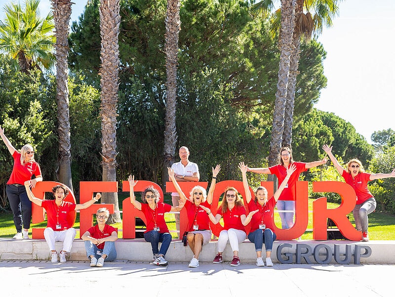 Touristiker-Gruppe vor Dertour-Logo