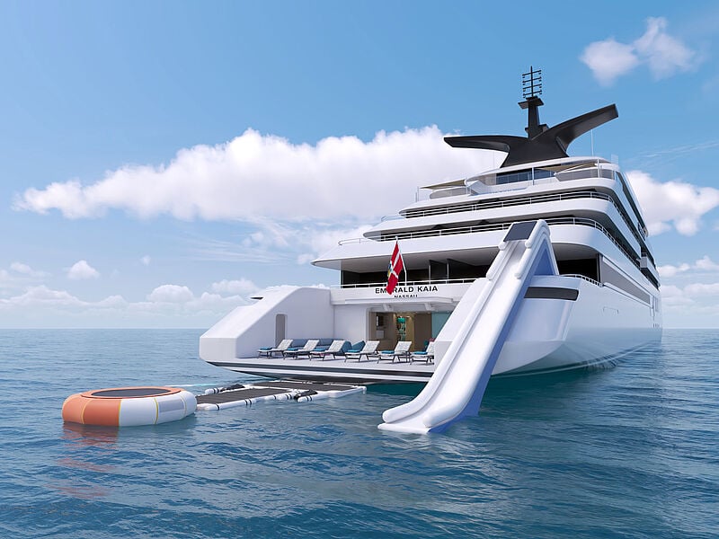 Vom Heck einer Superyacht führt eine aufblasbare Wasserrutsche direkt ins Meer. Daneben treibt eine schwimmende Marina am Heck, die Schwimmern den Zugang ins Meer erleichtern soll.