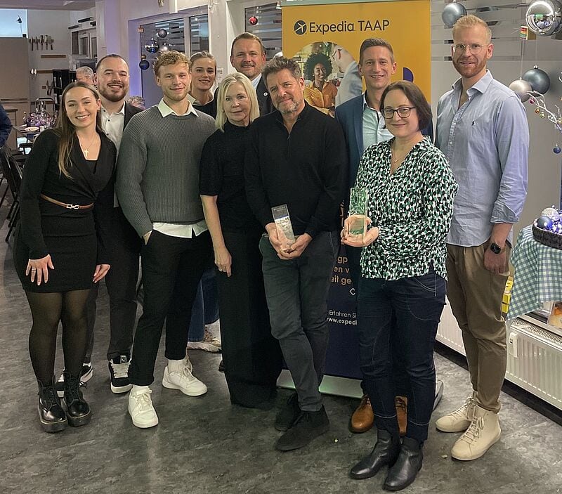 Zehn Personen stehen vor einem TAAP Schild