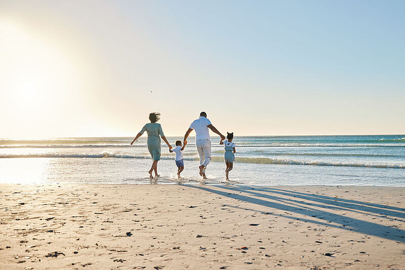 Eltern mit zwei Kindern an einem Sandstrand