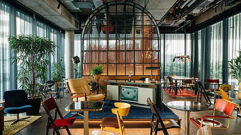 Viele unterschiedliche, bunte Stühle vor einer Bar