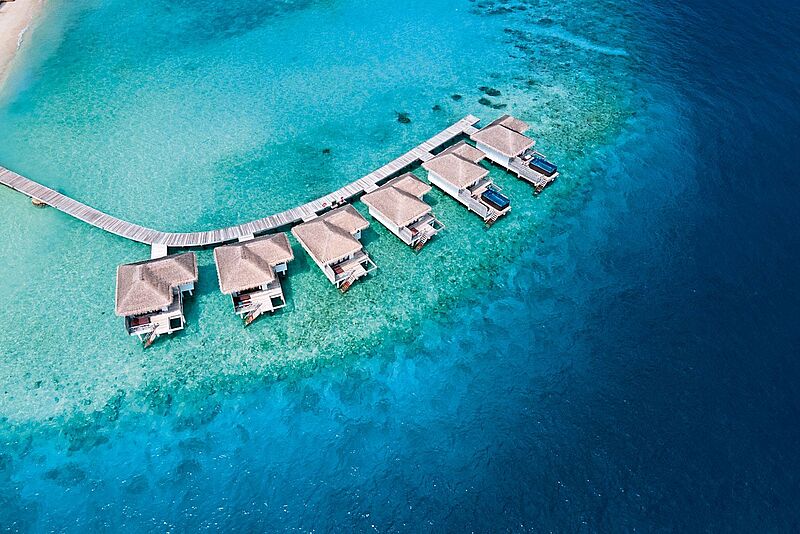 Sechs Overwater-Villen in türkisgrünem Wasser von oben