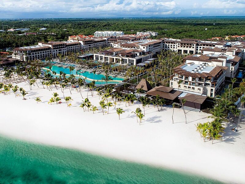 Ein großes Hotelgebäude an einem feinsandigen Strand.
