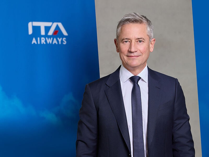 Porträt von Jörg Eberhart vor einem Logo von ITA Airways