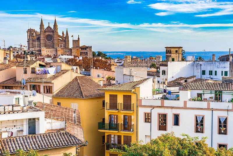 Panoramablick über Palmas Altstadt mit der gotischen Kathedrale La Seu, bunten Stadthäusern und dem Mittelmeer im Hintergrund.