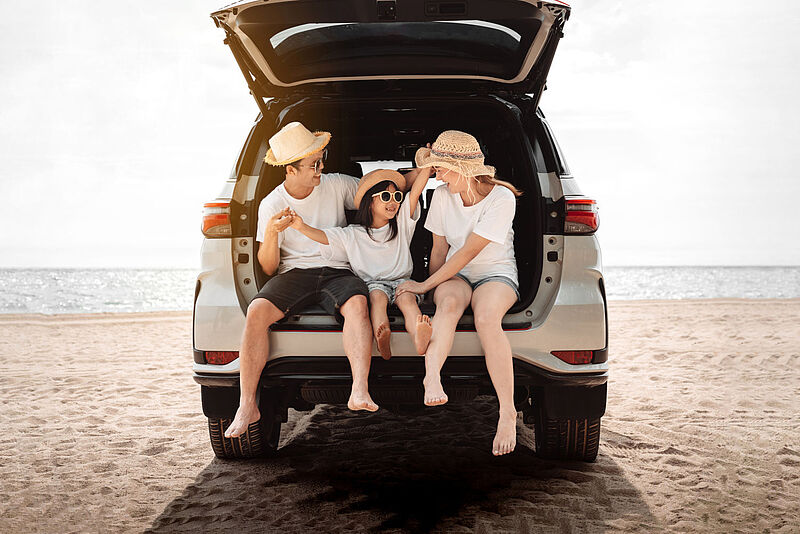 Eine Familien sitzt im Kofferraum eines Autos am Strand