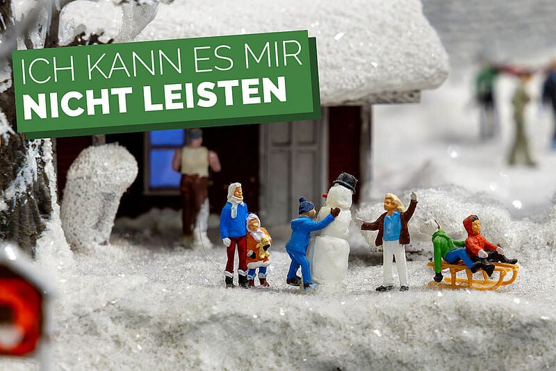 Kleine Plastikfiguren auf Kunstschnee mit Schriftzug „Ich kann es mir nicht leisten“
