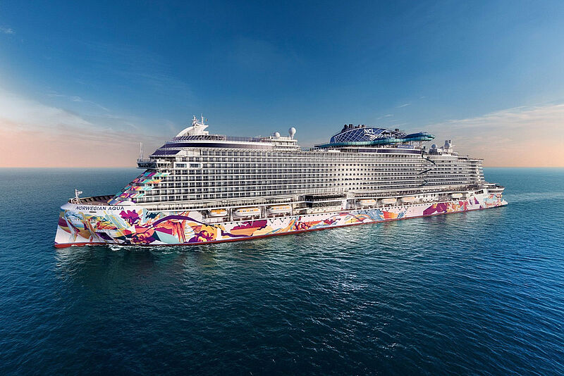 Kreuzfahrtschiff Norwegian Aqua auf offener See mit markanter bunter Kunstbemalung am Rumpf