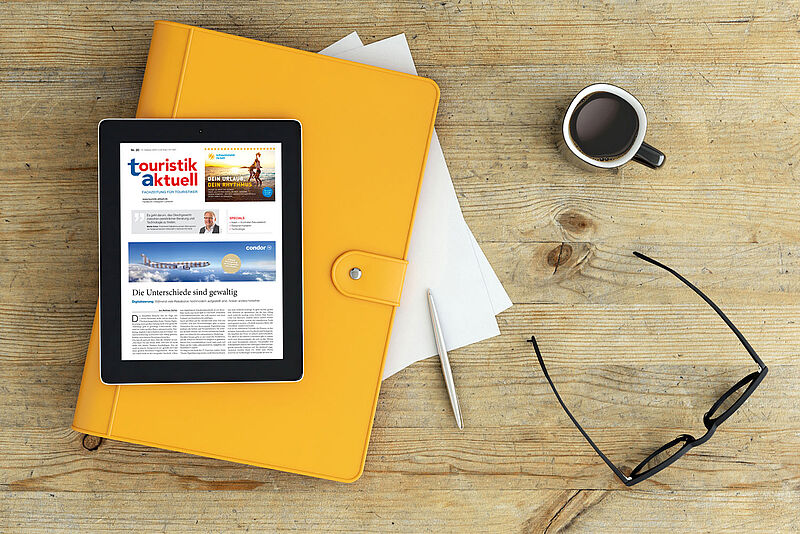 Schreibtisch mit Tablet mit Fachzeitschrift touristik aktuell