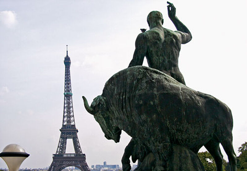 Hercules und Stier blicken auf den abendlichen Eiffelturm.