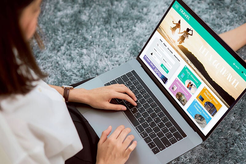 Frau bucht Reise online am Laptop