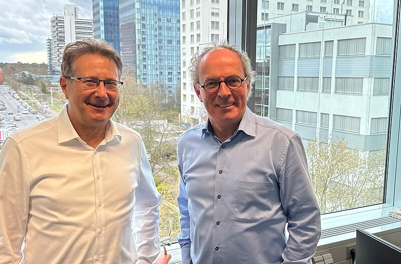 Die Geschäftsführer des ADAC Reisevertriebs, Aquilin Schömig und Andreas Neumann, stehen vor einem Fenster