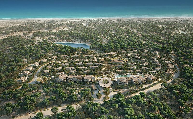In einer weitläufigen hügeligen Dünen-Landschaft am Meer befindet sich ein Hotel mit vielen einzelnen Gebäuden.
