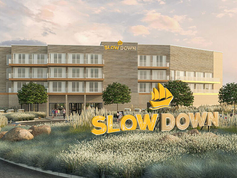 Ein neuerbautes Hotel mit Solar-Panel auf dem Dach, daneben ist ein Swimmingpool