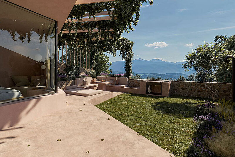 Rittstein Homes in Eppan: Terrasse mit Pergola, Naturstein und Rankpflanzen; großes Fenster mit Landschaftsblick, Slow Luxury.