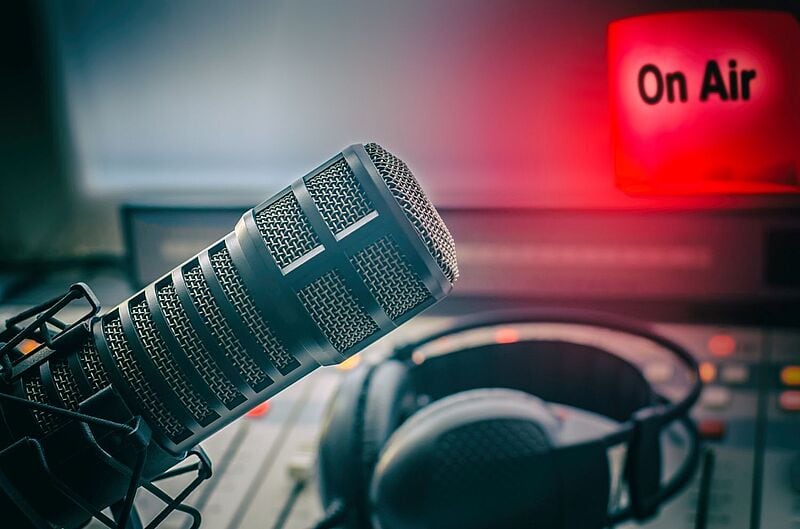 Ein Foto von einem Mikrophon im Hintergrund ein leuchtend rotes Schild mit on air