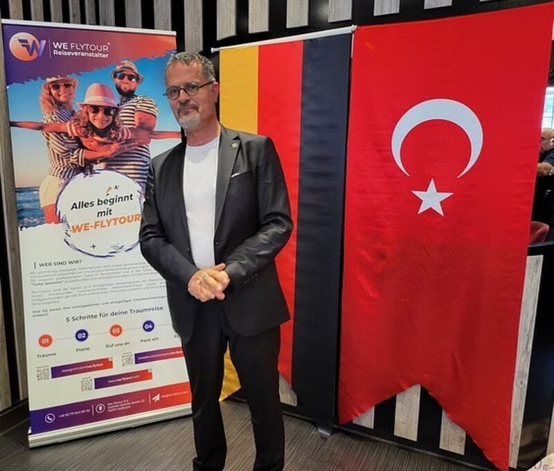 Mann steht vor einer deutschen und einer türkischen Flagge