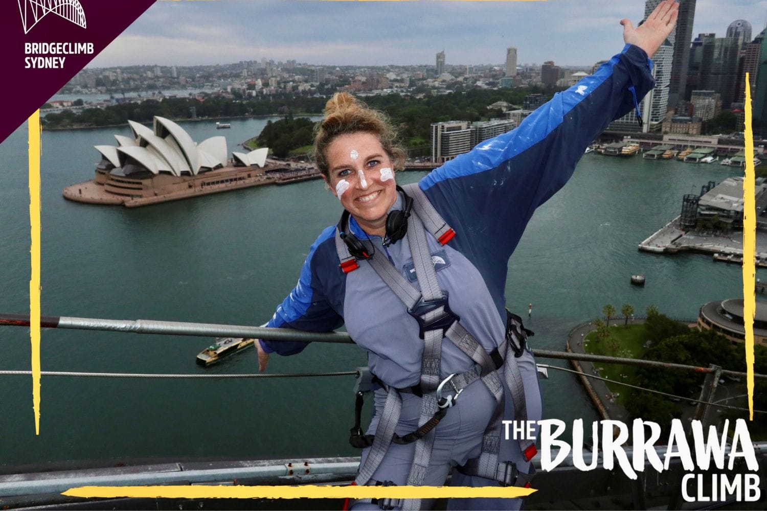 Eine Frau in einem grauen Sicherheitsanzug mit Klettergeschirr steht auf der Sydney Harbour Bridge und lächelt in die Kamera. Im Hintergrund sind das Sydney Opera House und die Skyline von Sydney zu sehen. Auf dem Bild steht „BridgeClimb Sydney“ und „The Burrawa Climb“.