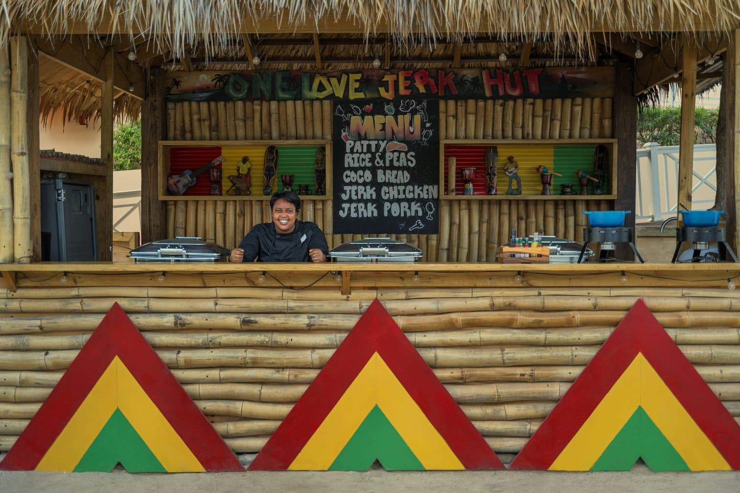 Bunter Imbiss mit Jerk-Chicken und traditioneller jamaikanischer Küche in Strandhütte mit Reggae-Dekor