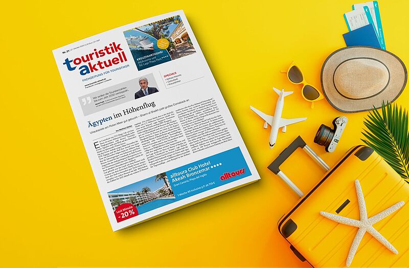 Titelblatt der Fachzeitung touristik aktuell mit der Schlagzeile „Ägypten im Höhenflug“ liegt auf einem gelben Hintergrund. Daneben befinden sich Reiserequisiten wie ein gelber Koffer mit Seestern, Sonnenhut, Kamera, Sonnenbrille, Flugzeugmodell und Reisedokumente – Symbol für Urlaub und Reiselust.