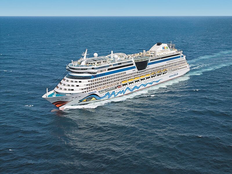 Das Kreuzfahrtschiff Aida Bella fährt bei Sonnenschein auf offenem Meer