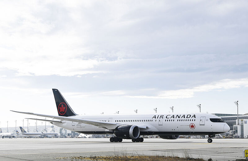 Ein Langstreckenflugzeug von Air Canada steht auf dem Rollfeld am Flughafen München vor bewölktem Himmel.