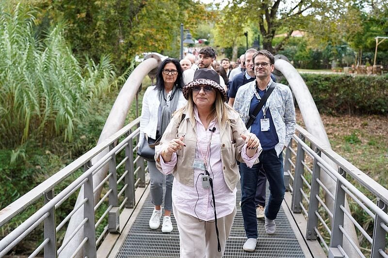 Eine Frau mit Hut führt Menschen durch Olympia