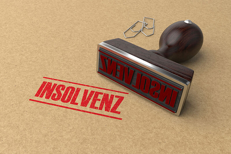 Stempel mit dem Schriftzug Insolvenz und Büroklammern