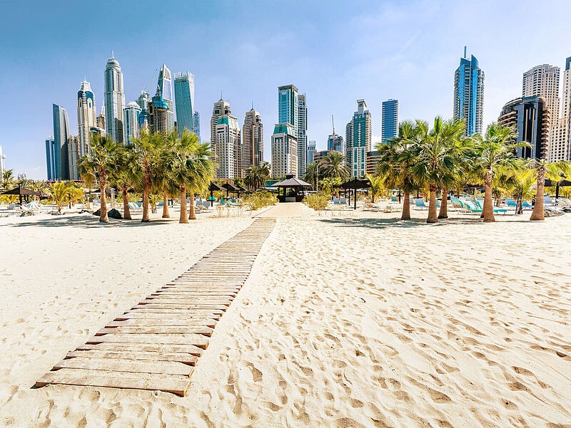 Skyline von Dubai mit Hochhäusern, im Vordergrund ist Strand zu sehen