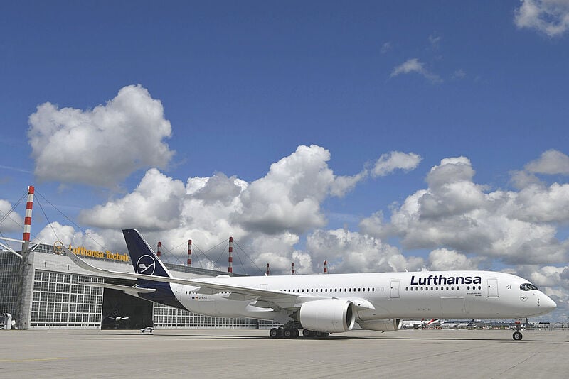 Ein Flugzeug vom Typ Airbus A350 von Lufthansa in weiß-blauer Lackierung steht vor einem Hangar der Lufthansa Technik