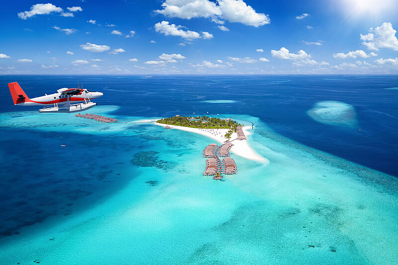 Wasserflugzeug über kleiner Malediveninsel mit Overwater-Bungalows
