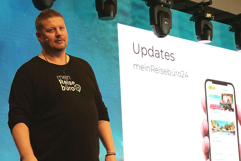 Mann auf Bühne mit großem Bildschirm