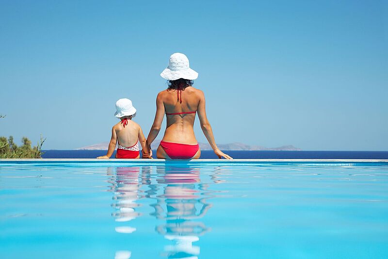 Frau und Kind in Badebekleidung an einem Infinity-Pool