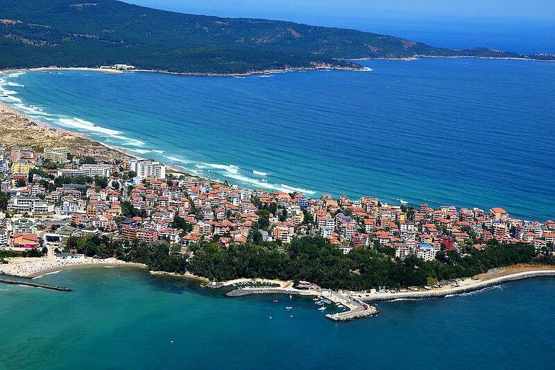 Stadt an Schwarzmeerküste mit Strand und Bergen im Hintergrund im Sonnenschein