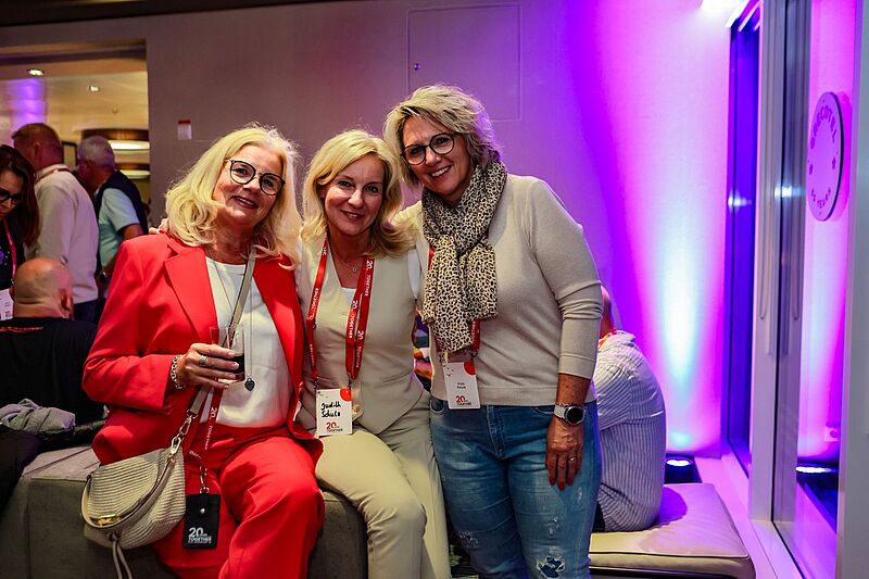 Drei Frauen in einem Raum, der in lilafarbenes Licht getaucht ist