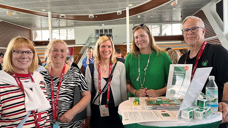 Vier Frauen und ein Mann stehen an einem Tisch und posieren für die Kamera