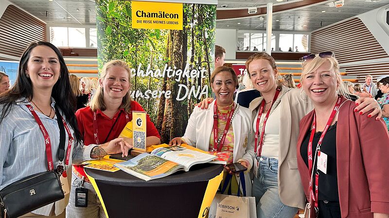Fünf Frauen an einem Stand blicken in die Kamera und lachen
