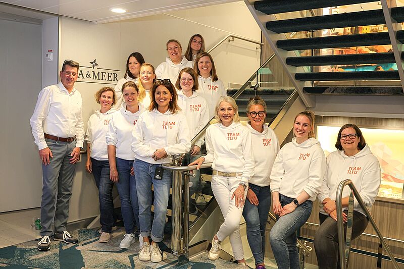 Viele Menschen im Treppenhaus eines Kreuzfahrtschiffs haben sich für ein Gruppenfoto zusammengestellt