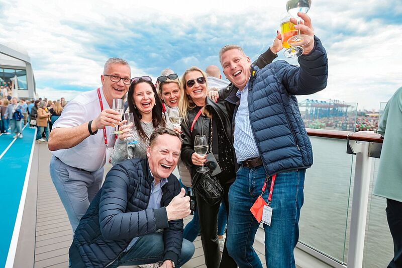 Ein Gruppenbild von mehreren Menschen, die zum Teil Gläser mit Getränken in der Hand halten