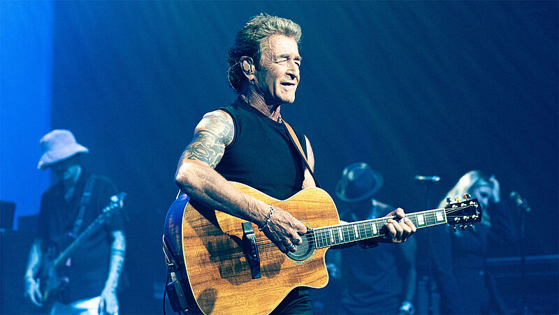 Sänger Peter Maffay mit Gitarre auf Konzertbühne