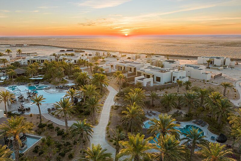 Luxuriöses Wüsten-Resort mit modernen Villen, Palmen, Pools und Sonnenuntergangspanorama am Rande der Sahara bei Tozeur, ideal für entspannenden Urlaub in Tunesien